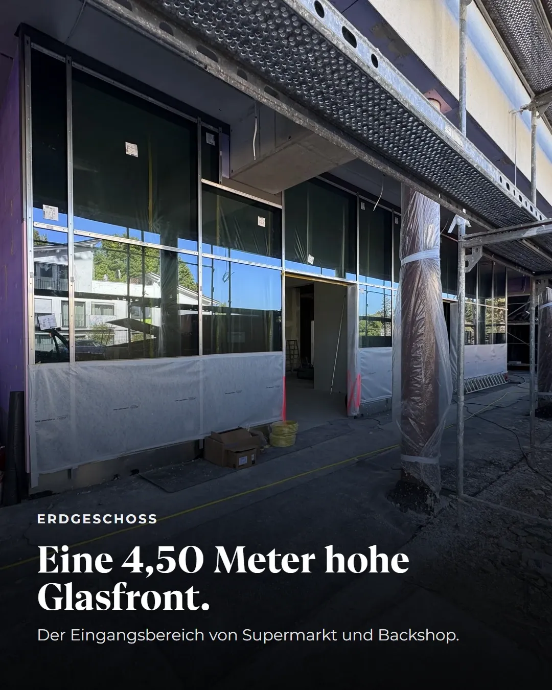 Erdgeschoss: Eine 4,50 Meter hohe Glasfront. Der Eingangsbereich von Supermarkt und Bäckerei. Blick auf die eingebaute, noch mit Folie geschützte Glasfassade.